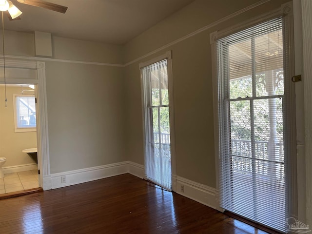 unfurnished room featuring ceiling fan, a healthy amount of sunlight, and dark hardwood / wood-style flooring