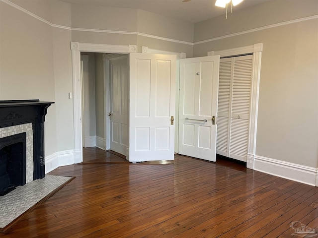 unfurnished bedroom with dark wood-type flooring, a fireplace, and a closet