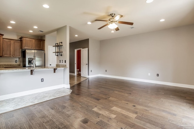 2107 Wilsons Plover Cir, Navarre, FL 32566 - kitchen featuring stainless steel fridge with ice dispenser, a ceiling fan, dark wood-style floors, light stone counters, and a breakfast bar area