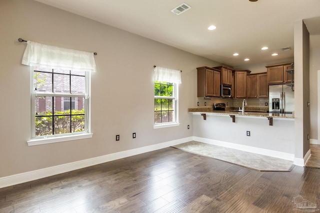 2107 Wilsons Plover Cir, Navarre, FL 32566 - kitchen featuring stainless steel appliances, wood finished floors, a kitchen breakfast bar, recessed lighting, and light stone countertops