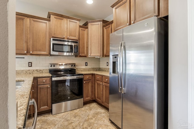 2107 Wilsons Plover Cir, Navarre, FL 32566 - kitchen with appliances with stainless steel finishes, backsplash, light stone counters, brown cabinets, and light tile patterned floors