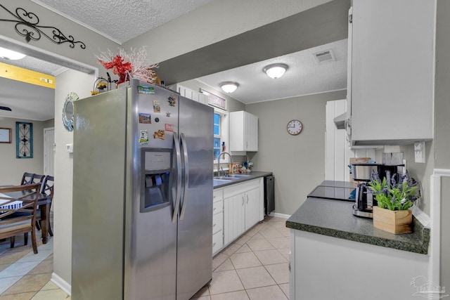 kitchen with stainless steel fridge, white cabinetry, sink, and a textured ceiling