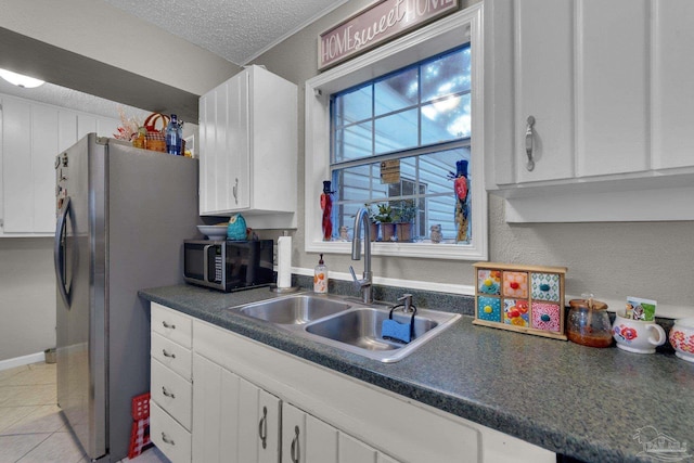 kitchen with sink, light tile patterned floors, a textured ceiling, white cabinetry, and stainless steel appliances