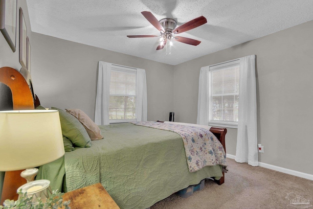 bedroom featuring multiple windows, a textured ceiling, light colored carpet, and ceiling fan