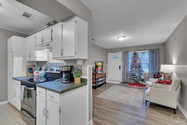 kitchen with stainless steel electric range, light hardwood / wood-style floors, white cabinetry, and a textured ceiling