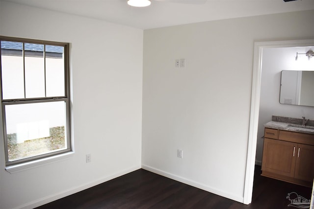 interior space with a sink, baseboards, multiple windows, and dark wood finished floors