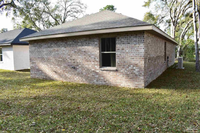 view of property exterior with a yard, central AC unit, brick siding, and roof with shingles