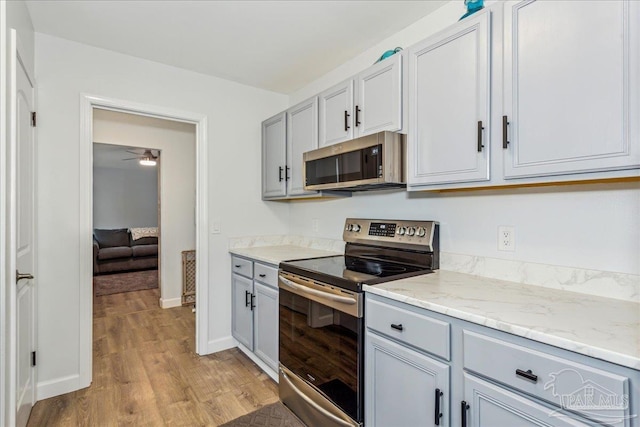 7244 Frankfort St, Navarre, FL 32566 - kitchen with appliances with stainless steel finishes, gray cabinetry, ceiling fan, light stone counters, and light wood-type flooring