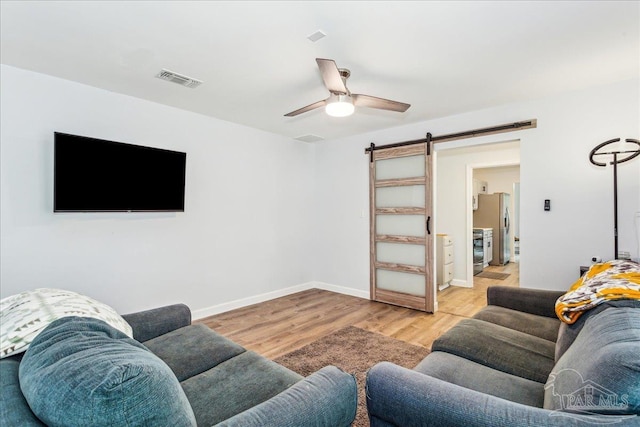 7244 Frankfort St, Navarre, FL 32566 - living room with ceiling fan, a barn door, and light wood-type flooring