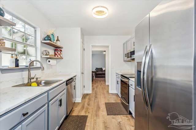 7244 Frankfort St, Navarre, FL 32566 - kitchen featuring sink, gray cabinets, appliances with stainless steel finishes, light stone counters, and light wood-type flooring