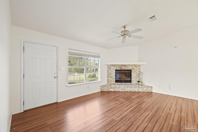 5362 Barbarosa Rd, Gulf Breeze, FL 32563 - unfurnished living room with a ceiling fan, a brick fireplace, wood finished floors, and visible vents