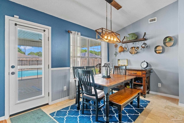 dining area with a textured ceiling, visible vents, vaulted ceiling, baseboards, and a chandelier