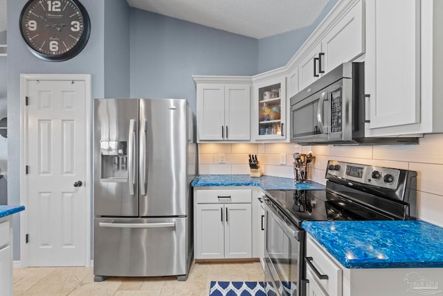 kitchen with glass insert cabinets, white cabinets, tasteful backsplash, and stainless steel appliances