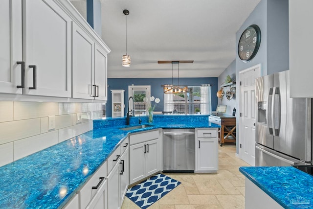 kitchen featuring decorative backsplash, a sink, a peninsula, stainless steel appliances, and stone tile floors
