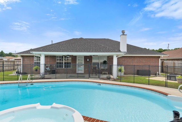 view of swimming pool featuring a yard, a pool with connected hot tub, and fence