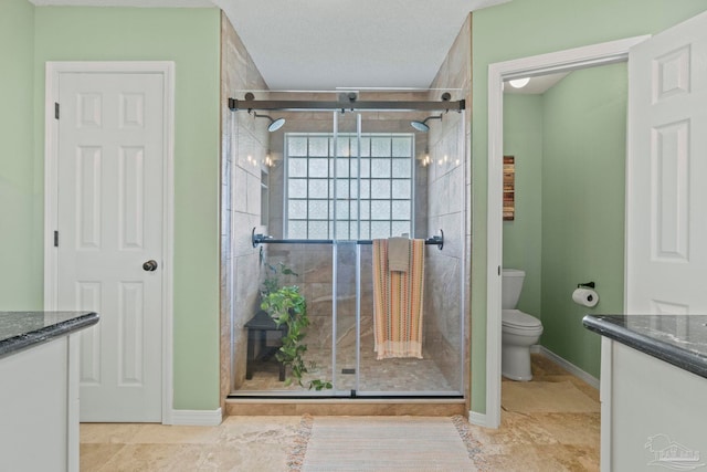 bathroom with vanity, baseboards, a stall shower, and toilet