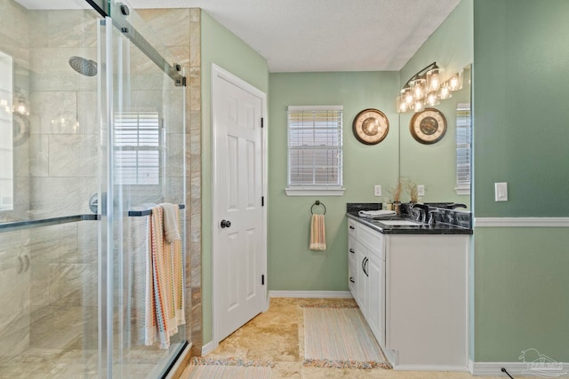 bathroom with vanity, baseboards, and a stall shower
