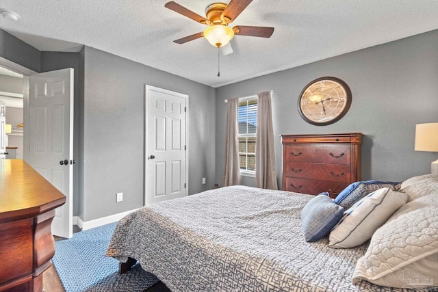 bedroom featuring baseboards, a ceiling fan, a textured ceiling, and a textured wall