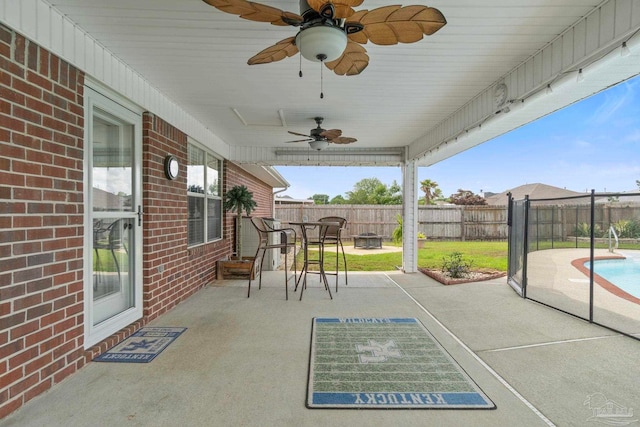 view of patio featuring a ceiling fan, a fire pit, a fenced backyard, and a fenced in pool