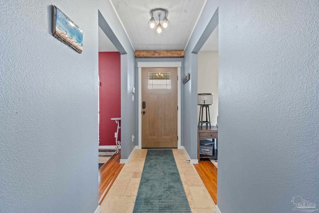 entryway featuring baseboards, a textured wall, and a chandelier