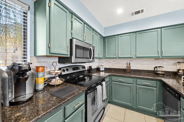 kitchen with light tile patterned floors, stainless steel appliances, visible vents, backsplash, and green cabinets