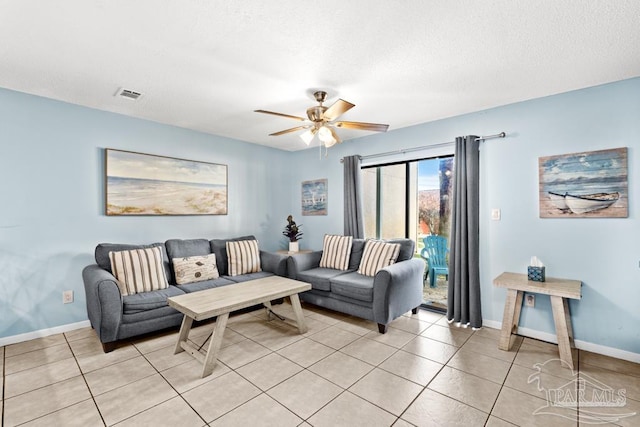 living room with light tile patterned floors, visible vents, baseboards, ceiling fan, and a textured ceiling