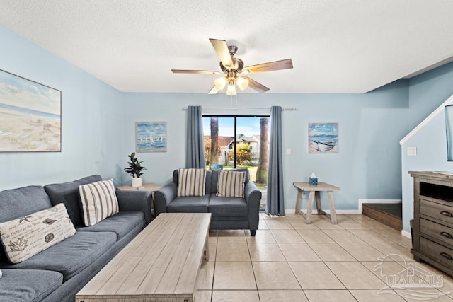 living area with a textured ceiling, light tile patterned flooring, a ceiling fan, and baseboards