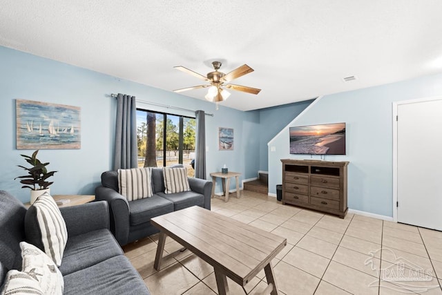 living area featuring a textured ceiling, light tile patterned flooring, visible vents, a ceiling fan, and baseboards