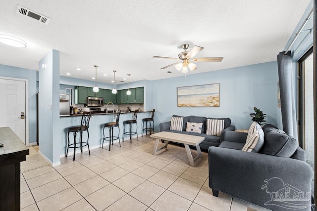 living room with light tile patterned floors, baseboards, visible vents, a ceiling fan, and recessed lighting