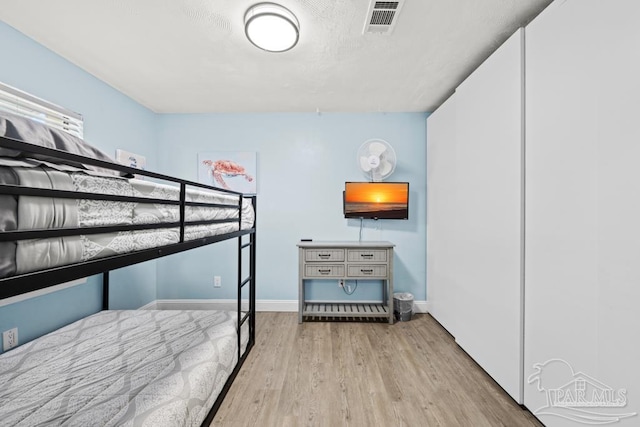 bedroom with wood finished floors, visible vents, and baseboards