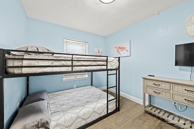 bedroom featuring light wood finished floors and baseboards