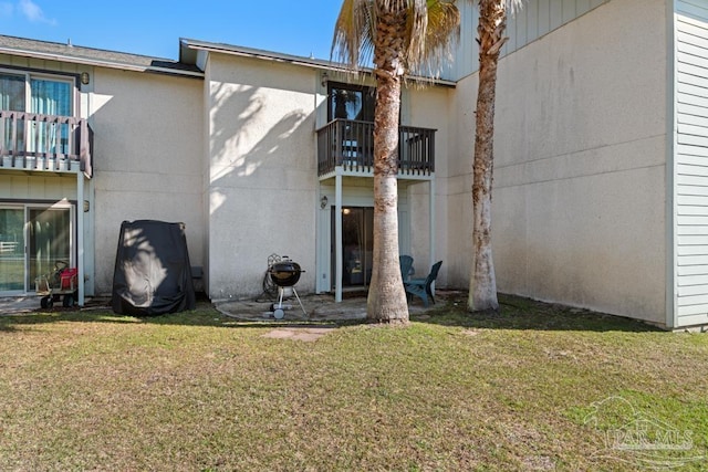 back of property featuring a balcony and a yard