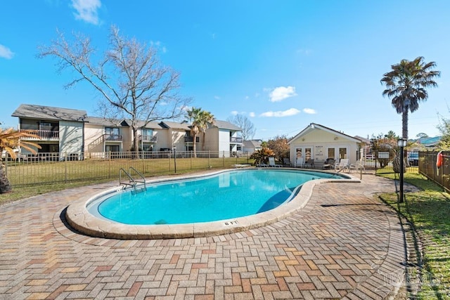 pool featuring a patio area, a residential view, fence, and a yard