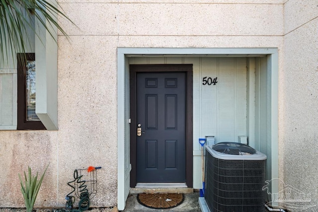 property entrance featuring central AC and stucco siding