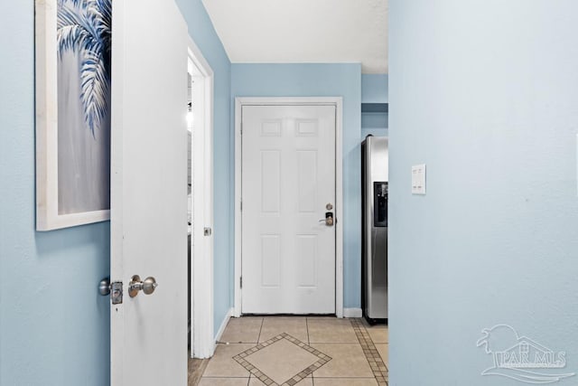 doorway to outside featuring light tile patterned floors and baseboards