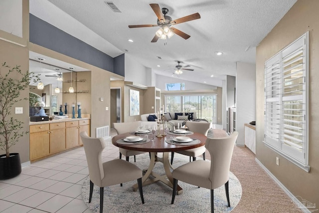 tiled dining space featuring a textured ceiling and lofted ceiling