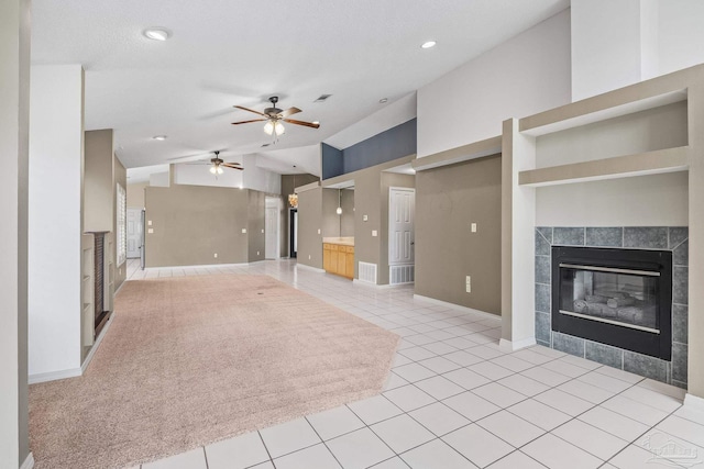 unfurnished living room featuring ceiling fan, light tile patterned flooring, and a tile fireplace