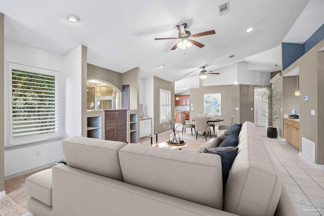 living room featuring a textured ceiling, ceiling fan, and a healthy amount of sunlight