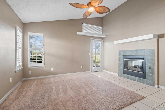 unfurnished living room featuring a tile fireplace, a textured ceiling, a wealth of natural light, and light tile patterned flooring