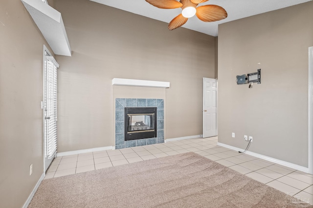 unfurnished living room with ceiling fan, light tile patterned floors, and a tile fireplace