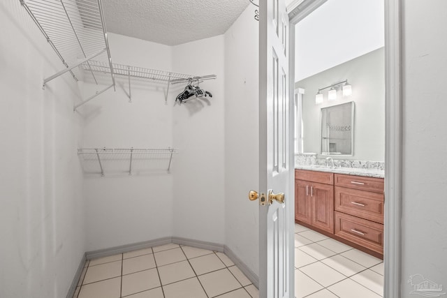 walk in closet featuring light tile patterned flooring and sink