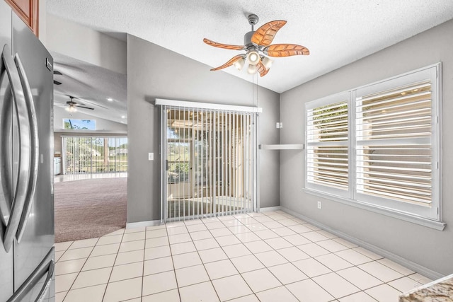 spare room featuring light tile patterned flooring, a textured ceiling, and vaulted ceiling