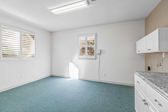 kitchen featuring white cabinetry, light carpet, and a textured ceiling