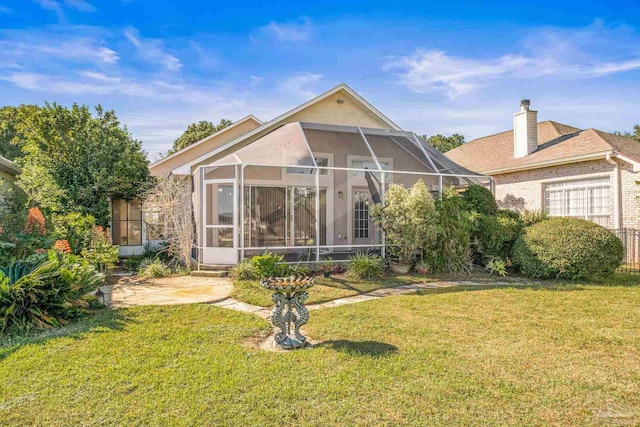 rear view of house with a lanai and a yard