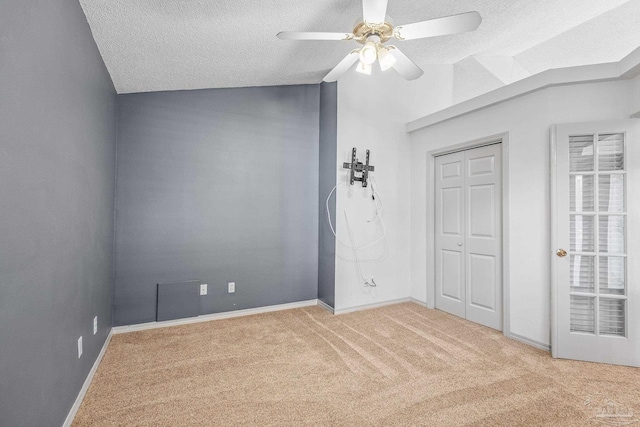 spare room with a textured ceiling, ceiling fan, carpet, and lofted ceiling