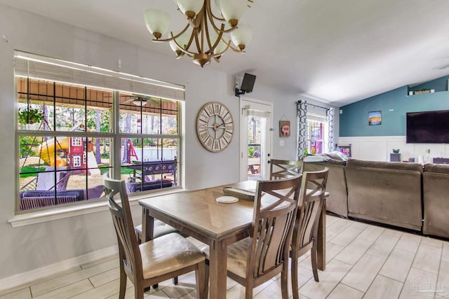 dining space with an inviting chandelier, wainscoting, and lofted ceiling