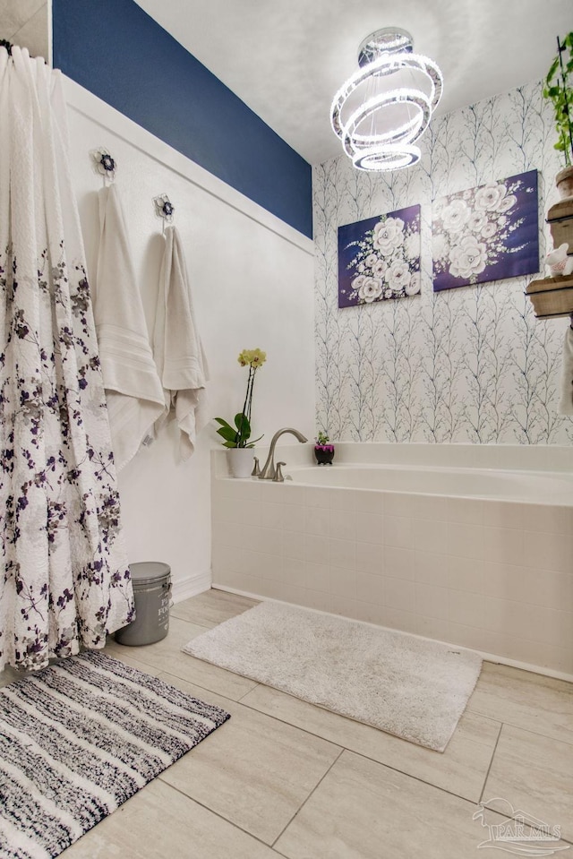bathroom featuring an inviting chandelier, a bath, an accent wall, and wallpapered walls
