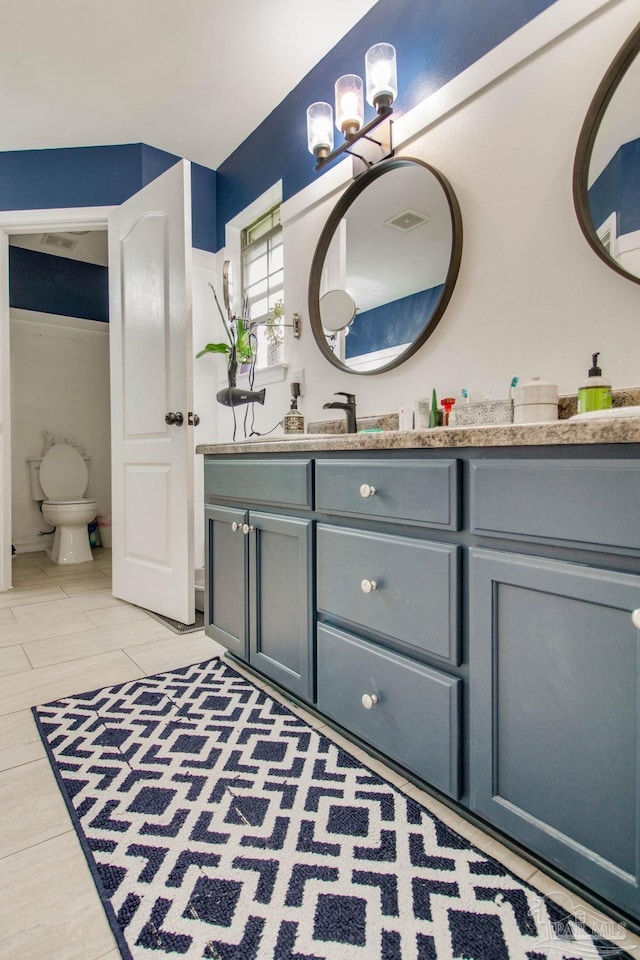 full bath with vanity, toilet, a chandelier, and visible vents