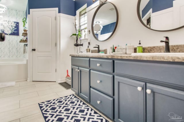 full bathroom with a sink, a bathtub, and double vanity