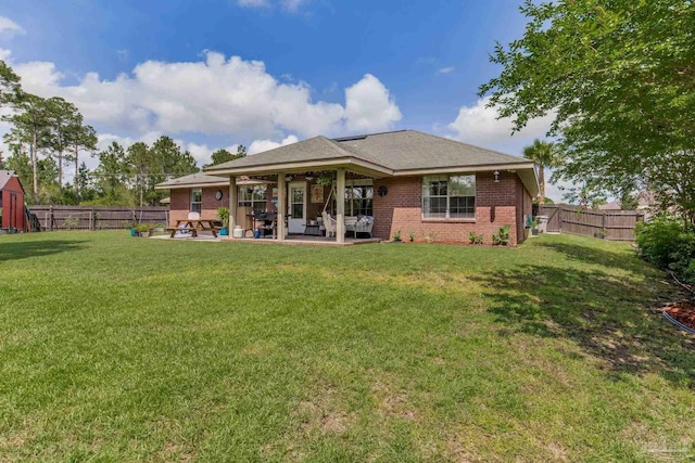rear view of house featuring a fenced backyard, a yard, a patio area, and brick siding